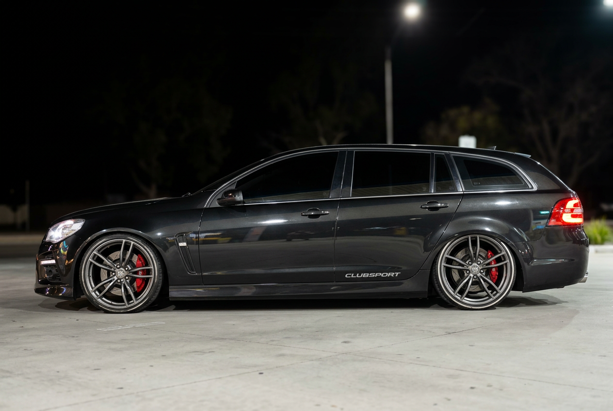 Dark HSV Clubsport wagon with aftermarket alloy wheels and red brake calipers at night
